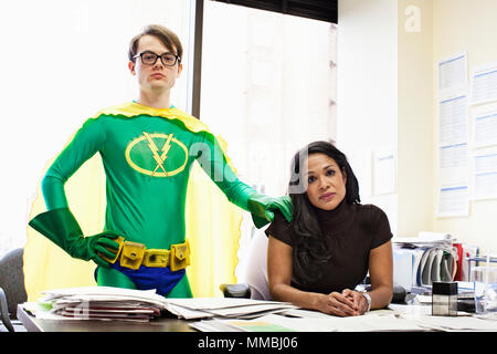 Une femme d'affaires noirs à son bureau avec son bureau caucasien conseiller de super héros. Banque D'Images