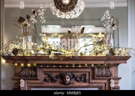 Close up de décorations de Noël sur la cheminée en bois magnifiquement sculpté, miroir au-dessus. Banque D'Images