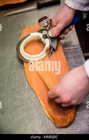 High angle close up de poissonnier à l'aide de slicer à trancher finement le filet de saumon. Banque D'Images