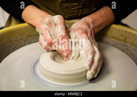 Close up of potter tablier portant sur les poteries de roue, façonner l'argile vase. Banque D'Images