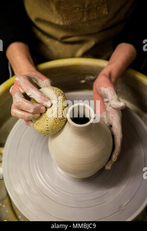 Close up of potter tablier portant sur les poteries de roue, façonner l'argile vase. Banque D'Images