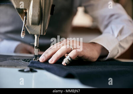 L'homme à l'aide d'une machine à coudre industrielle, de coutures d'un vêtement. Banque D'Images