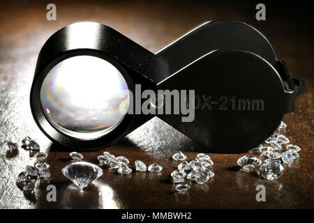 Diamants taille brillant avec loupe pliante sur fond de bois Banque D'Images