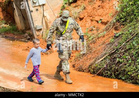 Spec. Leomar paredes de la Garde nationale de Porto Rico prend une pause de nettoyer les routes de passer quelques minutes avec un jeune garçon qui vivait dans les environs de Cayey, Puerto Rico. Paredes est un soldat dans le 190e bataillon du génie, qui a été attribué à dégager des routes à la suite de l'Ouragan Maria. Le bataillon travaille avec des soldats de la Garde nationale de Caroline du Sud pour rendre les routes plus accessible. (36) Maj photo Randall Stillinger Banque D'Images