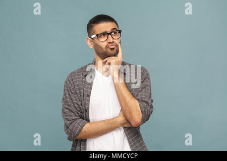 Portrait de bel homme sérieux barbu avec des lunettes noires style décontracté en pensée. studio shot sur fond bleu. Banque D'Images