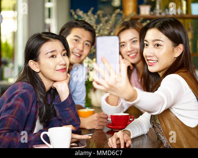 Groupe de jeunes adultes et les femmes asiatiques homme assis tenant un café. selfies Banque D'Images