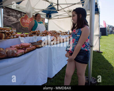 Une jeune fille se penche sur les pâtisseries en vente sur un étal du marché Banque D'Images