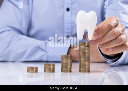 Man Placing Coin en haut de la pile de pièces en face de la Dent Blanche Banque D'Images