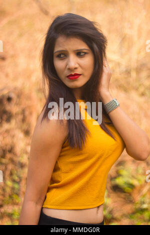 Femme élégante avec de longs cheveux bruns portant blouse jaune à côté Banque D'Images