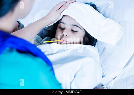 Sick Girl avec thermomètre fixant-lit et mère prendre la température de la fièvre Banque D'Images