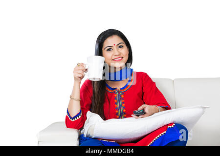 Une dame, femme au foyer à regarder la télévision et boire du thé assis canapé d'assistance à domicile Banque D'Images