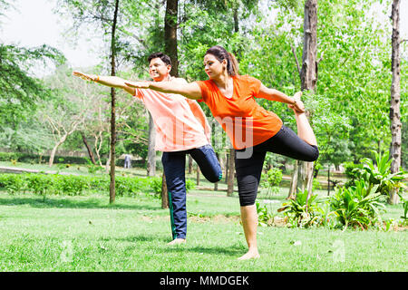 Deux Couple Doing Yoga Dhanurasana Dandayamana pratiquer des exercices matinaux Jardin Banque D'Images