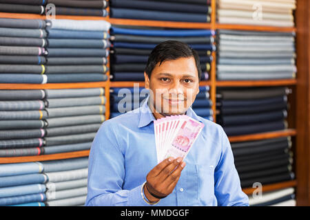 Un homme de vente de billets de roupies indiennes montrant Two-Thousand Marché Vêtements Banque D'Images