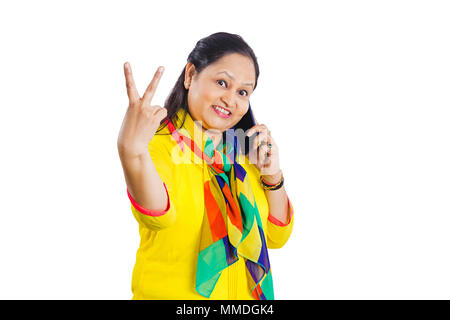 Une femme souriante Talking On Mobile phone aboutés, symbole de la Victoire Banque D'Images