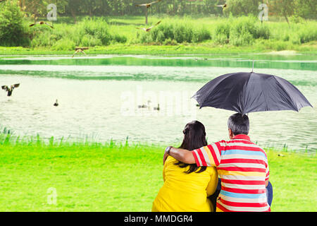 Du Couple sous l'herbe près du lac parapluie At-Park Banque D'Images