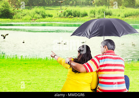 Vue arrière-Married-Couple Senior sous égide doigt montrant des oiseaux près du lac Banque D'Images