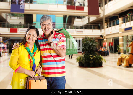 Happy Senior Couple Carrying Shopping Bags In-Mall Banque D'Images