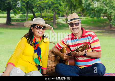 Deux amants Senior couple in love having picnic in-park avec guitare Banque D'Images