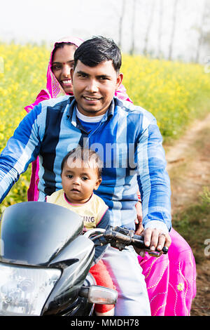 Agriculteur et sa mère avec son fils riding a motorcycle dans farm Village Banque D'Images