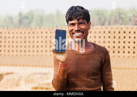 Un travailleur Homme montrant Smart phone dans l'usine de briques du Village Banque D'Images