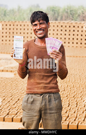 Un homme de main-d'argent montrant avec Aadhaar-Card Brick-Factory dans Village Banque D'Images