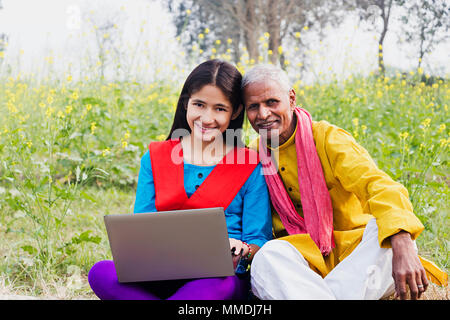 Villageois Rural, grand-père et fille de l'adolescence à l'aide d'ordinateur portable E-Learning In-Farm Banque D'Images