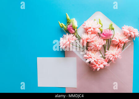 Le titre féminin télévision jeter sur fond bleu candy, vue du dessus.Un minimum de woman's desktop avec page blanche des maquettes, enveloppe, lisianthus roses, des chrysanthèmes. Concept créatif, carte de souhaits.Copy space Banque D'Images