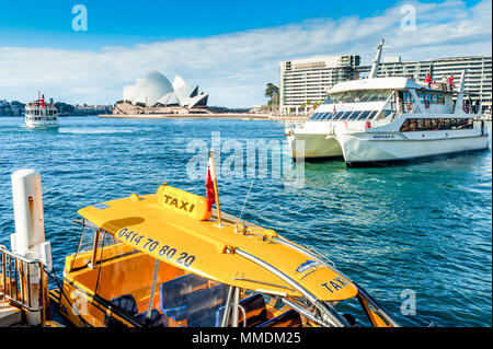 Ferry arrivant au terminal de ferries de Sydney Australie en été avec les touristes de l'après-midi profiter de la météo. Un bateau-taxi est mouillé à proximité. Banque D'Images