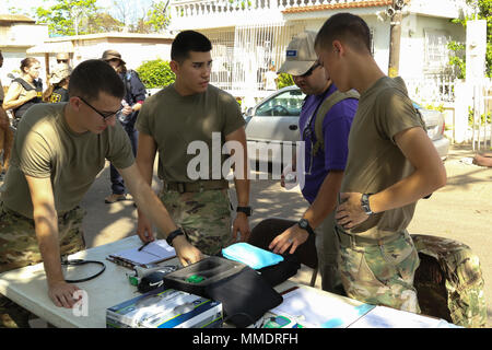 Trois spécialistes des soins de santé de l'armée affectés à la 285e Compagnie médicale (repas de soutien) préparer une gare de triage sur une rue résidentielle 21 oct., 2017, à Juana Diaz, Puerto Rico. Le personnel médical de la Garde nationale de l'Ohio a travaillé avec l'équipe d'aide médicale en cas de catastrophe (DMAT) d'organiser un programme de sensibilisation afin de fournir aux membres de la communauté qui ne pouvait pas voyager à la poste de secours mis en place à Ponce. L'équipe d'évaluation rapide (RAT) est doté de la même façon à un civil de soins urgents aux États-Unis, y compris des médecins, pharmaciens et autres membres du personnel médical. La Garde nationale de l'Ohio (photo par le Sgt. Joanna Banque D'Images