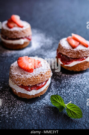 Mini Victoria sponge cakes traditionnels avec de la crème fouettée et les fraises Banque D'Images