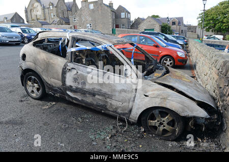 Voiture brûlée en parking avec ruban de police autour de lui Banque D'Images