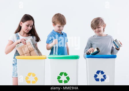 Séparer les enfants de papier, verre et métal en jaune, vert et les bacs bleus Banque D'Images