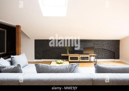 La télévision sur le mur de brique noire, debout devant une table gris in modern living room interior Banque D'Images