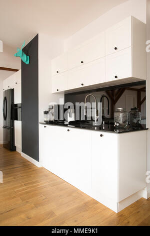 Vue de côté cuisine intérieur blanc avec comptoir et plancher en bois noir Banque D'Images