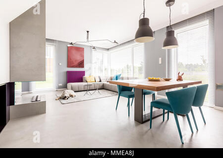 Appartement lumineux à l'intérieur design moderne avec sol en bois, une table beige et bleu des chaises de créateur Banque D'Images