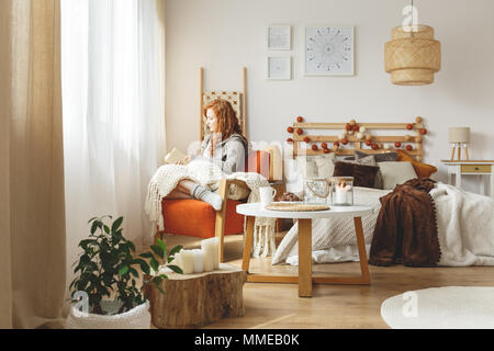 Jeune femme assise dans un fauteuil avec une couverture Banque D'Images