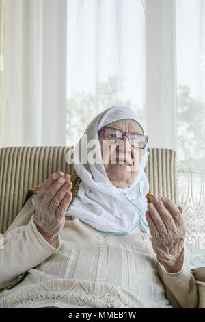 Une musulmane senior woman wearing scarf en priant Banque D'Images