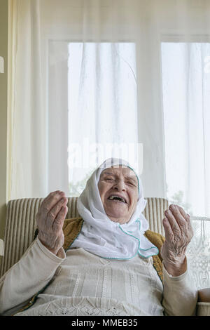 Une musulmane senior woman wearing scarf en priant Banque D'Images