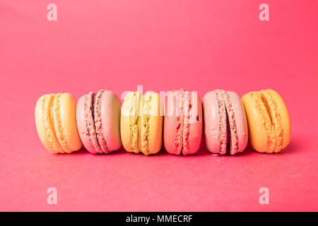 Macarons dans une ligne sur un fond rose Banque D'Images