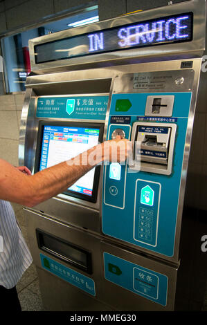 L'homme le passage des pièces dans un distributeur de billets sur le métro de Pékin à Beijing, Chine. Banque D'Images