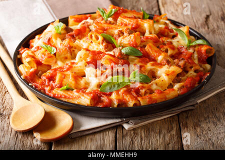 Les pâtes faites maison en cocotte avec la viande hachée, les tomates, les herbes et le fromage sur une plaque sur une table horizontale. Banque D'Images