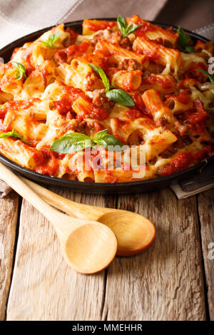 Pâtes ziti cuit avec de la viande hachée, de tomate et de fromage sur une assiette sur la table verticale. Banque D'Images