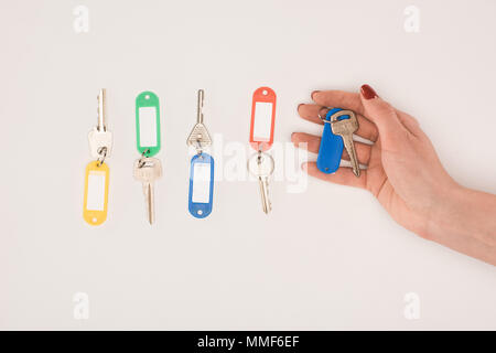 Vue du dessus de la main maintenant la touche à côté de jeu de clés avec des étiquettes colorées isolé sur blanc Banque D'Images