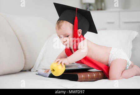 Cute baby boy in graduation cap vers de pomme jaune. Concept de l'éducation des jeunes enfants Banque D'Images