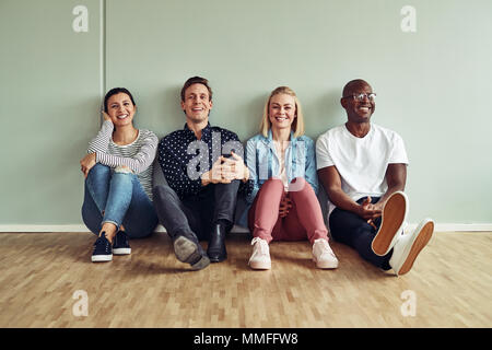 Rire de groupe d'affaires diversifié assis ensemble à l'étage d'un bureau pendant la pause Banque D'Images