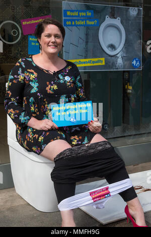 Londres, Royaume-Uni. Le 11 mai, 2018. Un militant de dystrophie musculaire UK abaisse son pantalon et s'assoit sur les toilettes à l'extérieur d'un magasin de vente de produits de bain dans le centre de Londres pour sensibiliser le public d'un mauvais services pour personnes à mobilité réduite. Credit : Mark Kerrison/Alamy Live News Banque D'Images