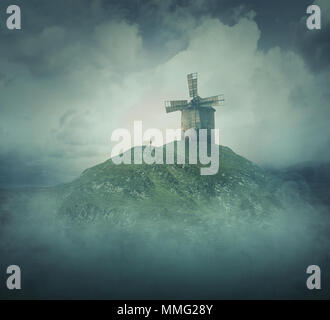 Vue paysage comme une dérive de la silhouette de fille se tenir en face d'un ancien moulin à vent sur le sommet d'une colline entourée de brouillard et de nuages. Voyage de la vie, concept st Banque D'Images