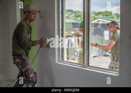 Un soldat de l'Armée Philippine sands l'intérieur d'un bâtiment que les Marines américains affectés à la 9e, 3e Bataillon d'appui du Groupe Logistique Maritime peindre les murs extérieurs durant la construction dans le cadre de l'exercice Balikatan à Calangitan Elementary School de CAPAS, Tarlac, Philippines, le 6 mai 2018. Exercice Balikatan, dans sa 34e version, est un américain annuel-exercice d'entraînement militaire des Philippines a porté sur une grande variété de missions, y compris l'assistance humanitaire et les secours en cas de catastrophe, la lutte contre le terrorisme, et d'autres opérations militaires conjointes tenues du 7 mai au 18 mai. (U.S. Photo par Marine Co Masse Banque D'Images