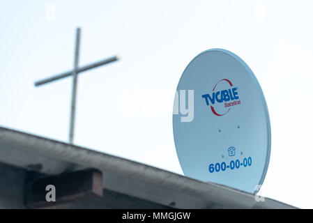 Antenne satellite sur le toit d'une maison et d'une croix au sommet d'une église voisine, Puerto Villamil, îles Galapagos, en Équateur. Banque D'Images