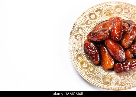 Dattes séchées sur un plateau traditionnel sur un fond blanc. Ramadan Kareem Banque D'Images